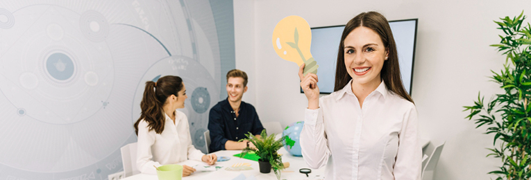 Three people are seen, with one holding a bulb-shaped 'Idea' sign, while two others sit behind and engage in conversation.